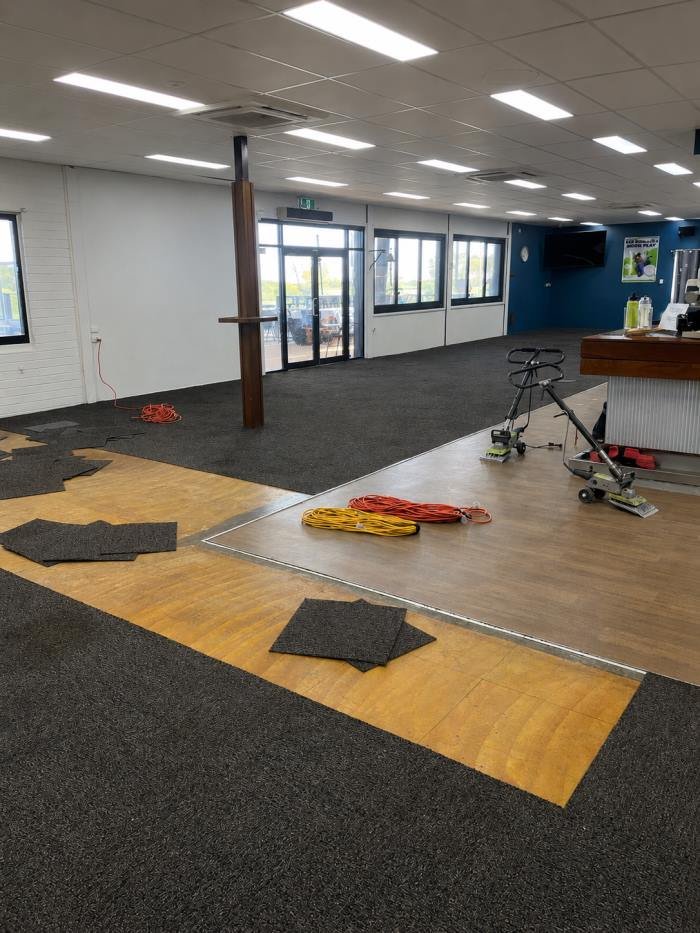 Carpet tiles pulled up, subfloor exposed