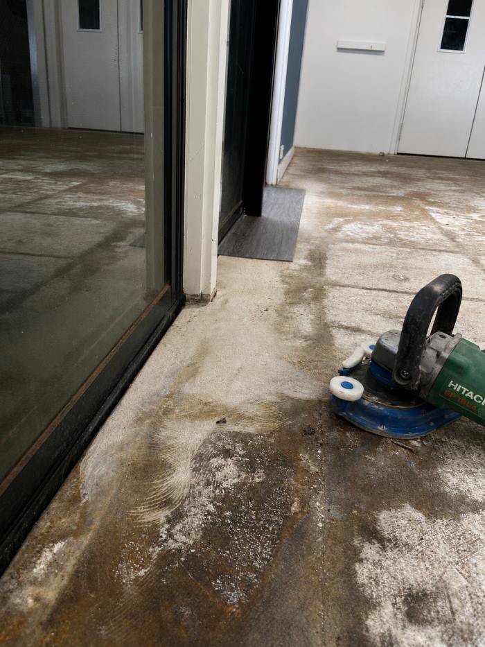 Concrete subfloor being ground near a doorway